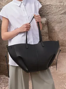 Detalle del bolso tote de cuero negro con correas delgadas y detalles de cordones laterales
