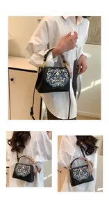 Close-up of black crossbody bag with colorful floral embroidery and silk scarf handle