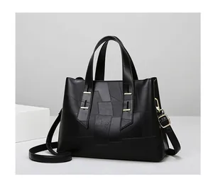 Detail of black leather tote bag featuring geometric stitching and gold-tone metal hardware