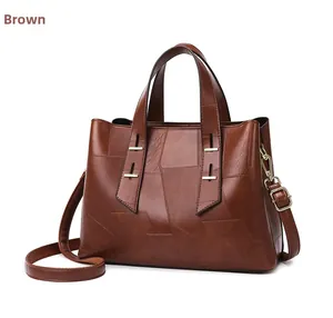 Close-up of brown matte leather tote bag with geometric stitching and gold hardware