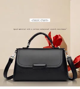 Detail van zwarte crossbodytas met kiezelstructuur en metalen gesp op beige achtergrond