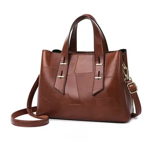 Detailed side view of brown leather tote bag with geometric stitching and gold hardware