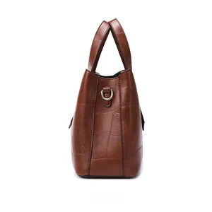 Detailed side view of brown leather tote bag with patchwork design and metal D-rings