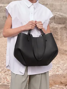 Detalle de bolso tote de cuero granulado negro con estructura arquitectónica plegable
