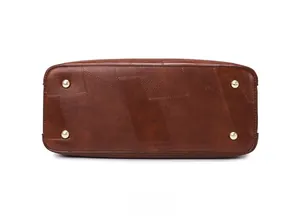 Detailed view of brown tote bag bottom with four gold protective metal studs and stitching