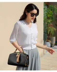 Elegante borsa Boston nera con manici marroni abbinata a cardigan bianco e pantaloni