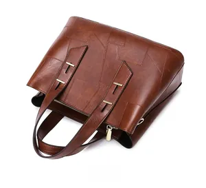 Close-up of brown tote bag showing irregular leather stitching and gold hardware details