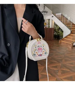 Detail of white round crossbody bag with traditional Chinese floral embroidery on the front
