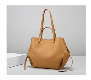 Detalle del bolso tote marrón con asas dobles y detalles de cordón ajustable lateral