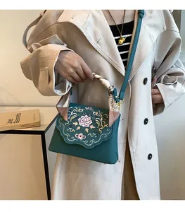 Detail of dark green handbag with Chinese floral embroidery and silk scarf handle wrap