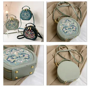 Close-up of vintage round crossbody bag with exquisite floral embroidery and golden zippers