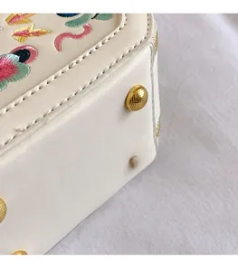 Detail of floral embroidery on leather bag and protective gold metal feet studs