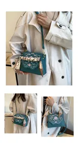 Detailed floral embroidery and scalloped edge flap on a vintage dark green crossbody bag