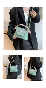 Detail of mint green crossbody bag featuring floral embroidery and silk scarf handle