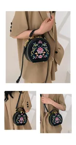 Detailed close-up of a black circular bag featuring intricate floral embroidery and gold hardware