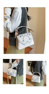 Detail of floral embroidery on cream crossbody bag with decorative silk scarf on handle
