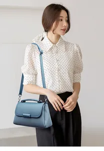 Grijsblauwe crossbodytas voor dames met litchi-patroon, gedragen door een model