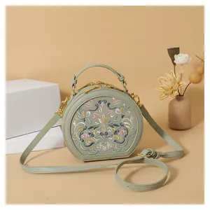 Detail of traditional floral embroidery on a sage green round crossbody handbag