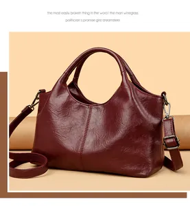 Detail van donker bordeauxrode leren handtas met dubbele handvatten en riem