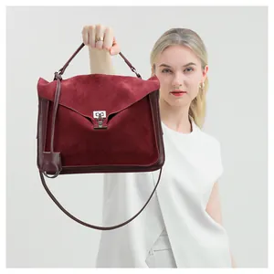 Detail of burgundy frosted leather handbag with silver twist lock and reinforced edges