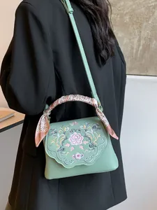 Mint green crossbody bag with floral embroidery and decorative scarf on handle