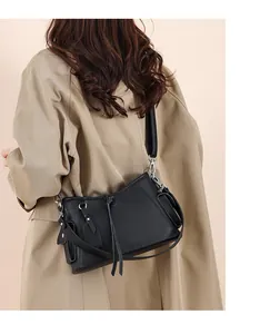 Detail view of black lychee grain leather shoulder bag with silver buckle and wide strap