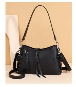 Close-up of litchi texture leather shoulder bag with decorative tassel and silver hardware