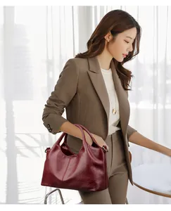 Detailopname van de bordeauxrode leren tas met fijne korrelstructuur en handgreepdetails