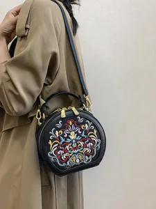 Elegant black crossbody bag with traditional floral embroidery and golden hardware detail
