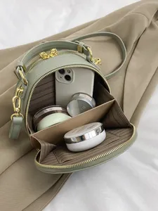 Green leather handbag with gold zipper showing internal compartments and soft lining