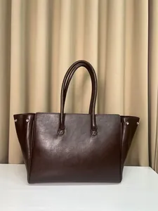 Detalle del bolso tote marrón oscuro con remaches plateados y acabado mate fino