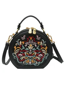 Black round crossbody bag with colorful floral embroidery and gold dual zipper design