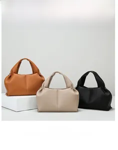 Detailed view of cloud tote bags in caramel brown, beige, and black lychee texture leather