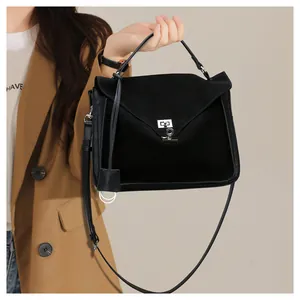 Detail view of black matte leather satchel featuring silver metal lock and top handle