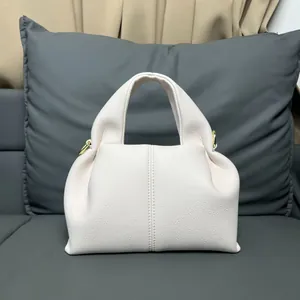 Detail of cream white leather handbag with textured pebble grain and gold metal hardware