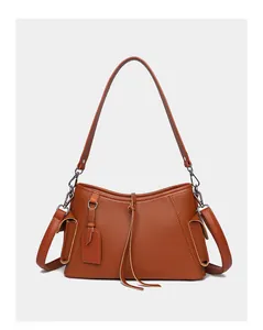 Detail view of caramel brown leather shoulder bag with lychee texture and side flap pockets