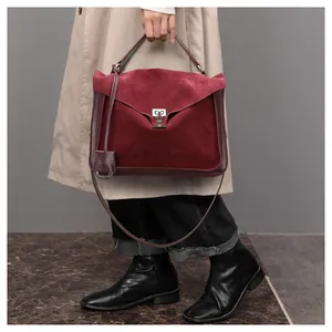 Detail of burgundy matte suede satchel bag with silver lock and elegant top handle