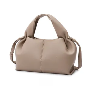 Detail view of lychee texture leather and gold hardware on beige crossbody tote bag