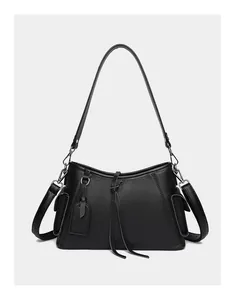 Detail of black lychee grain leather shoulder bag with side flap pockets and long tassels