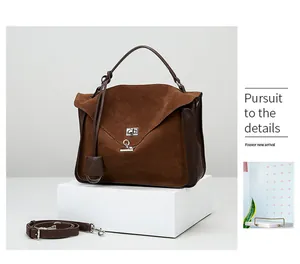 Detail view of brown matte suede messenger bag with silver lock and polished leather handle