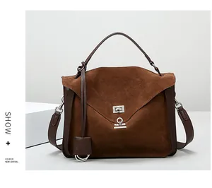 Detail view of brown matte suede satchel with metallic buckle and detachable leather strap