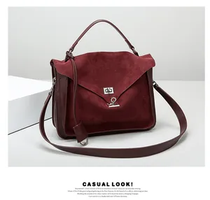 Close-up of matte burgundy suede satchel with silver twist lock and leather stitching