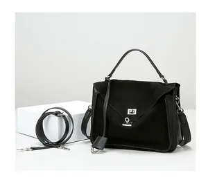 Detail of black frosted leather handbag with metallic turn-lock and adjustable strap