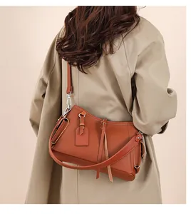 Close-up of brown leather shoulder bag with lychee texture and fringe detail