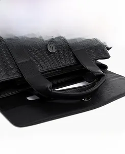 Close-up of woven leather handbag detail with magnetic snap closure and zip pocket