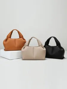 Three minimalist leather tote bags in caramel, beige, and black with a soft cloud structure