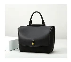 Close-up of black leather tote with a unique gold gourd-shaped lock and flap closure