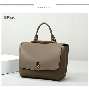 Detailed view of khaki leather tote with gold twist lock and sturdy handle on white stand
