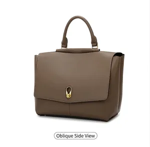 Side view detail of brown matte leather handbag with golden cylindrical metal lock