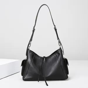 Detalle de bolso hobo negro con bolsillos laterales, cordón y correa ajustable